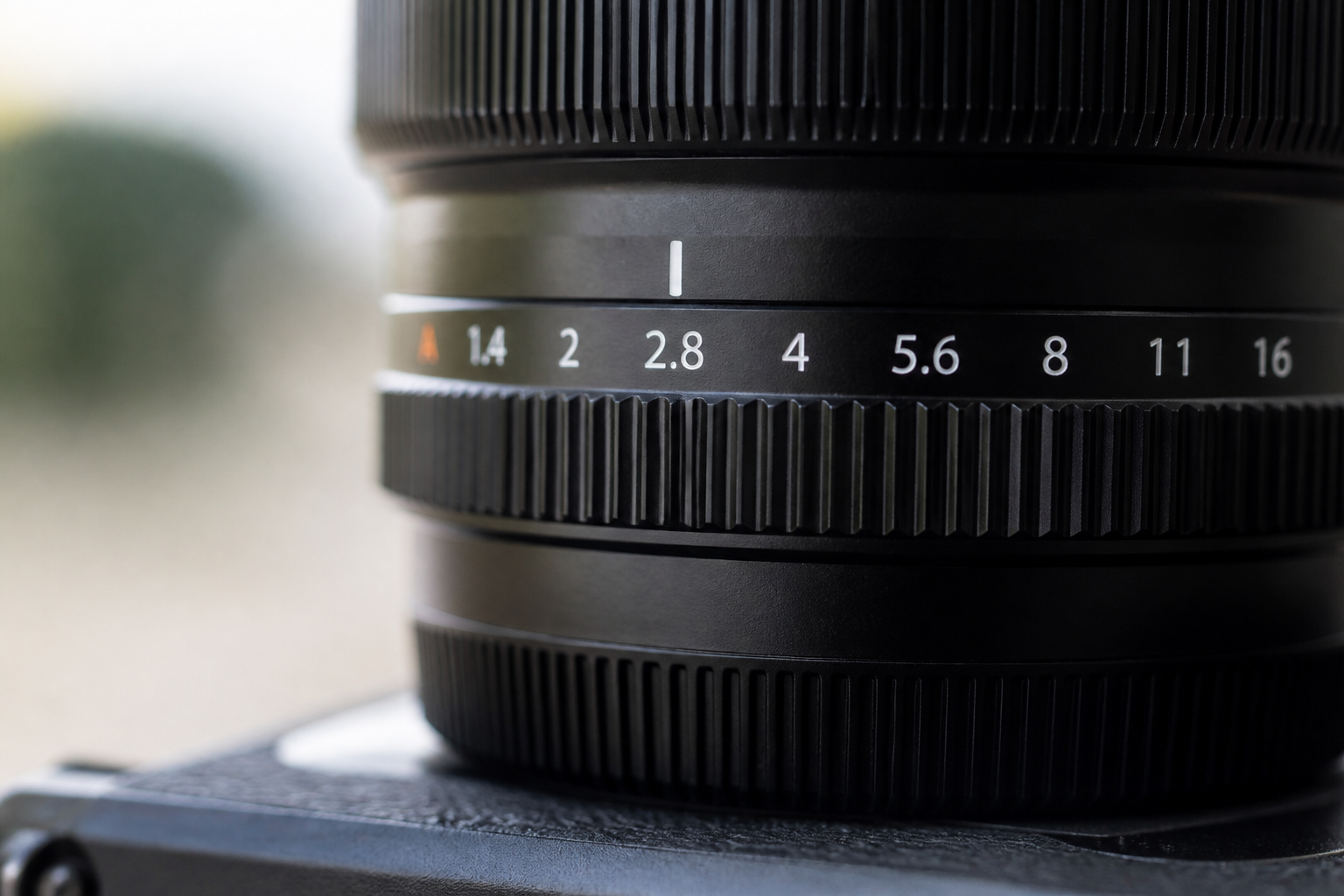 Gros plan sur la bague de diaphragme d'un objectif photo, graduée de f/1.8 à f/16, éclairée par une lumière rasante